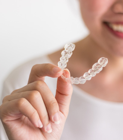Woman in white shirt holding clear aligner