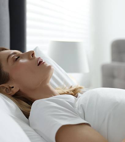 Woman with sleep apnea lying in bed snoring