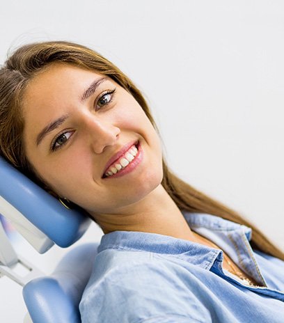 Woman with long brown hair smiling and sitting back in dental chair