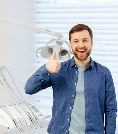 Bearded man giving thumbs up in dental office