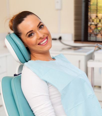 Female dental patient sitting in chair and smiling