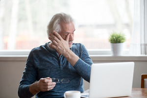 Man holding glasses and rubbing his dry eyes